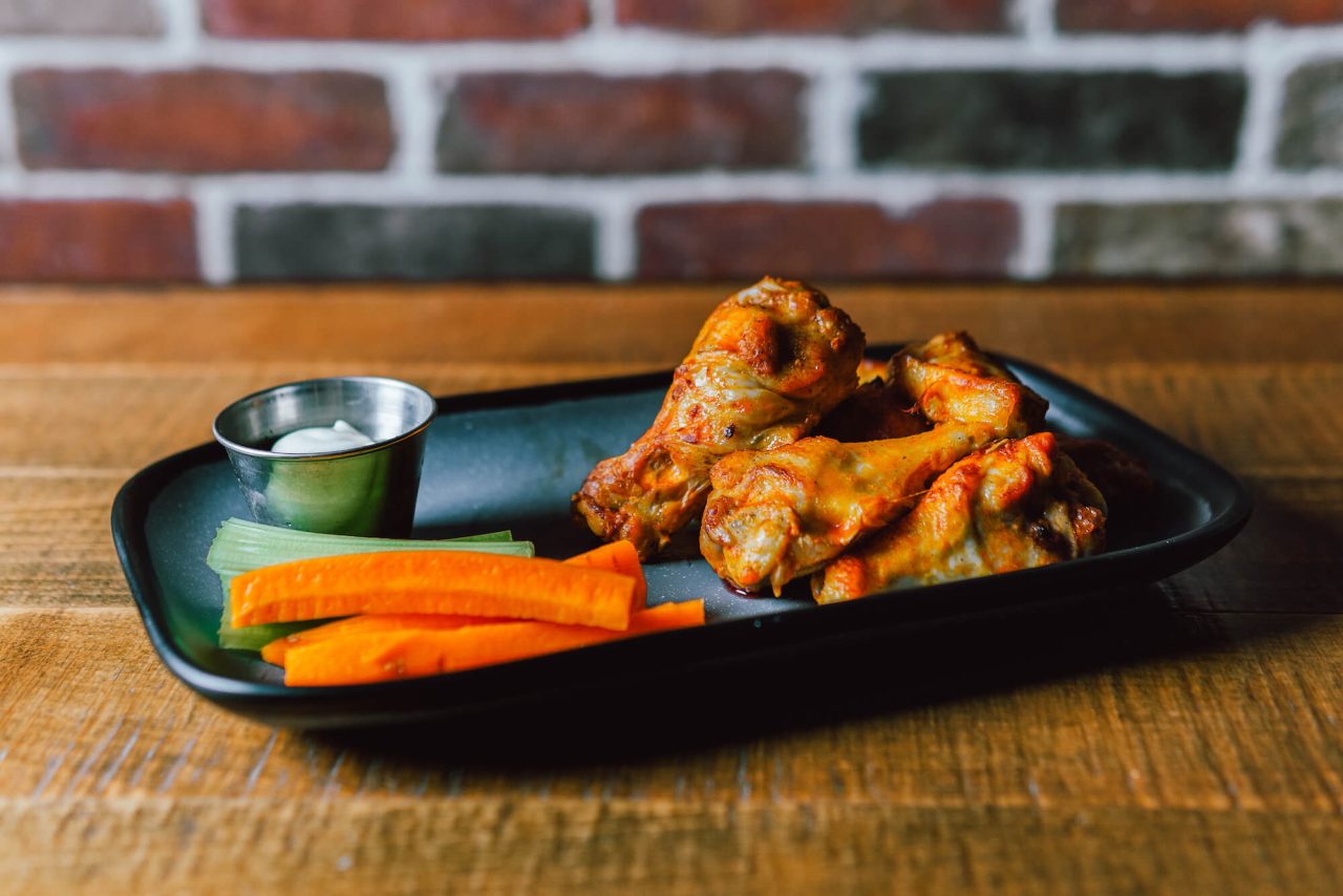 tray of buffalo wings with carrots and celery sticks