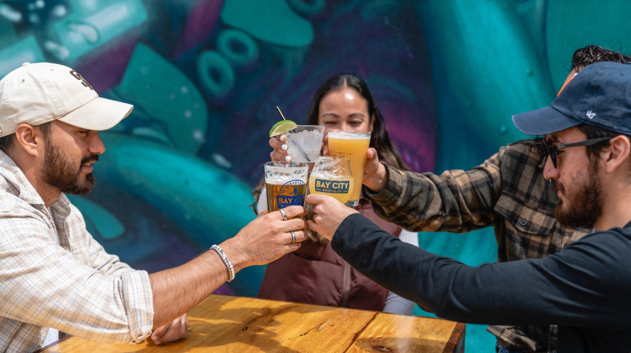 group of four customers raising drink glasses for a toast