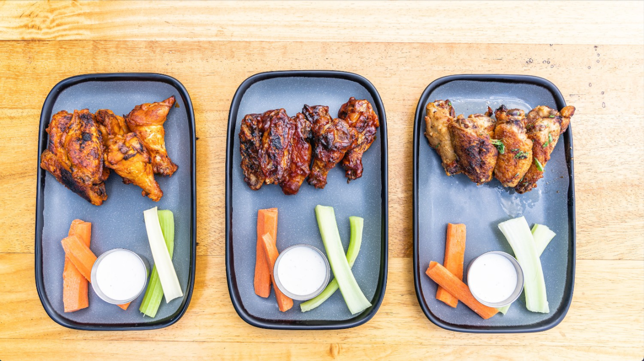 three plates of wings and veggies